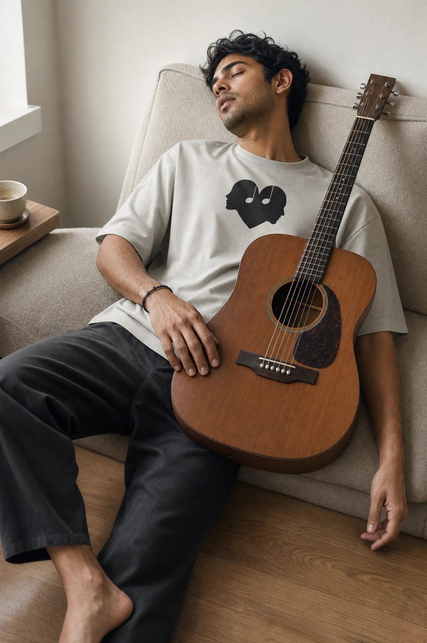 Man asleep with his guitar in the Ash Overture Oversized Tee