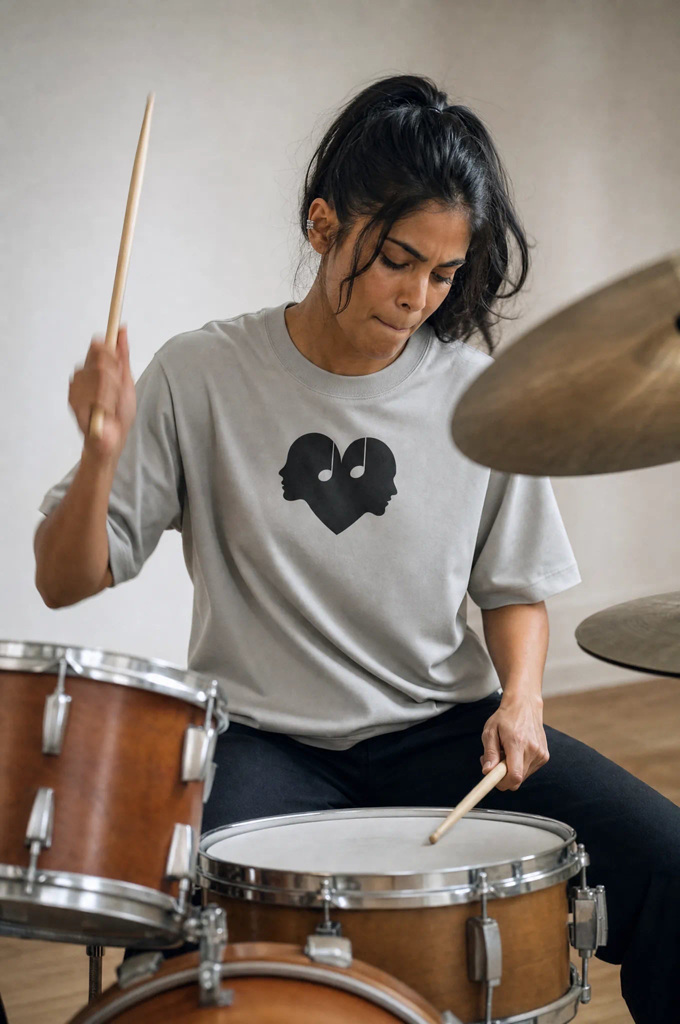 Woman playing drums in the Ash Overture Oversized Tee