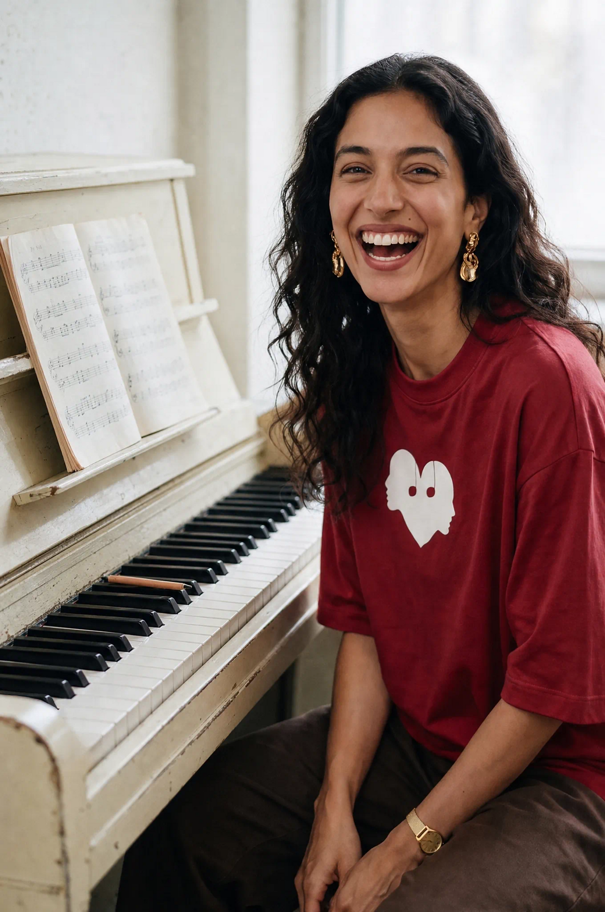 Woman laughing at a piano in the Crimson Overture Oversized Tee by Wear The Symbol