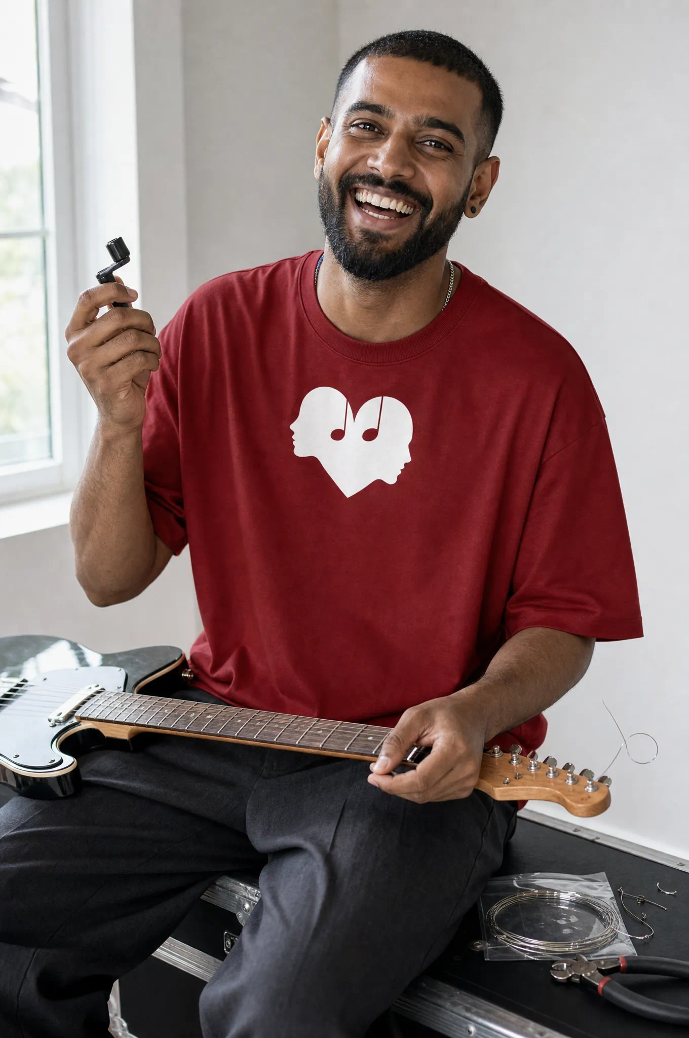 Man fixing a guitar in the Crimson Overture Oversized Tee