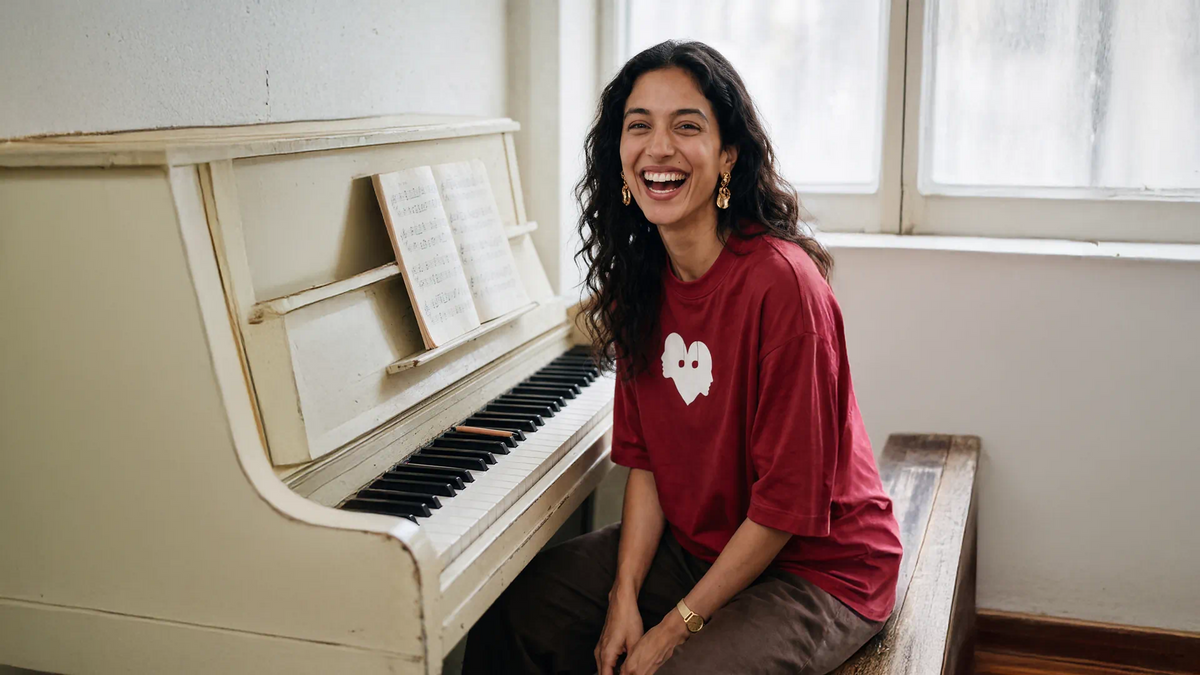 Woman laughing at a piano in the Crimson Overture Oversized Tee by Wear The Symbol