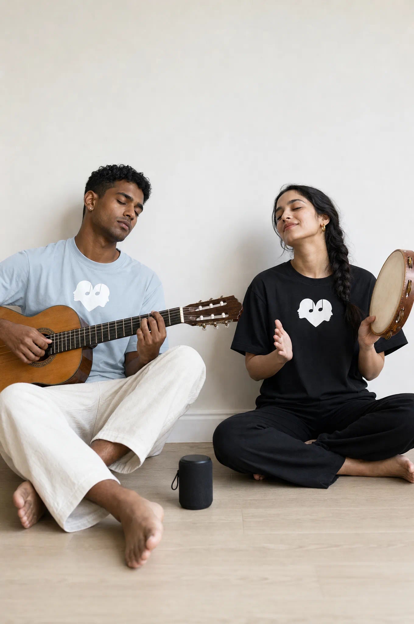 Duet of a woman in Horizon and a man in Piano Overture Oversized Tees playing tambourine and acoustic guitar