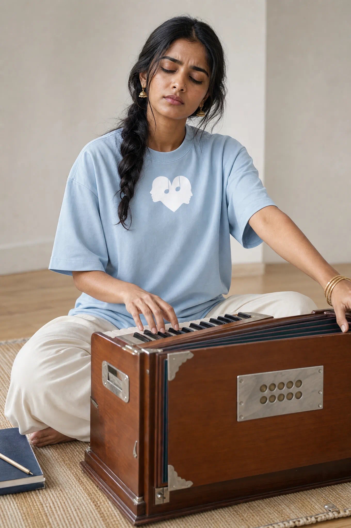 Woman playing the harmonium in the Horizon blue Overture Oversized Tee