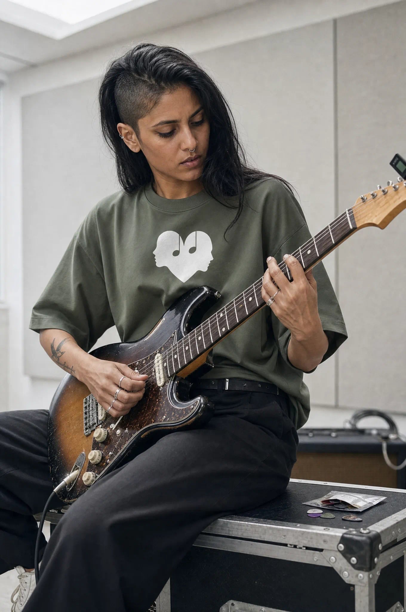 Woman playing an electric guitar in the Juniper green Overture Oversized Tee