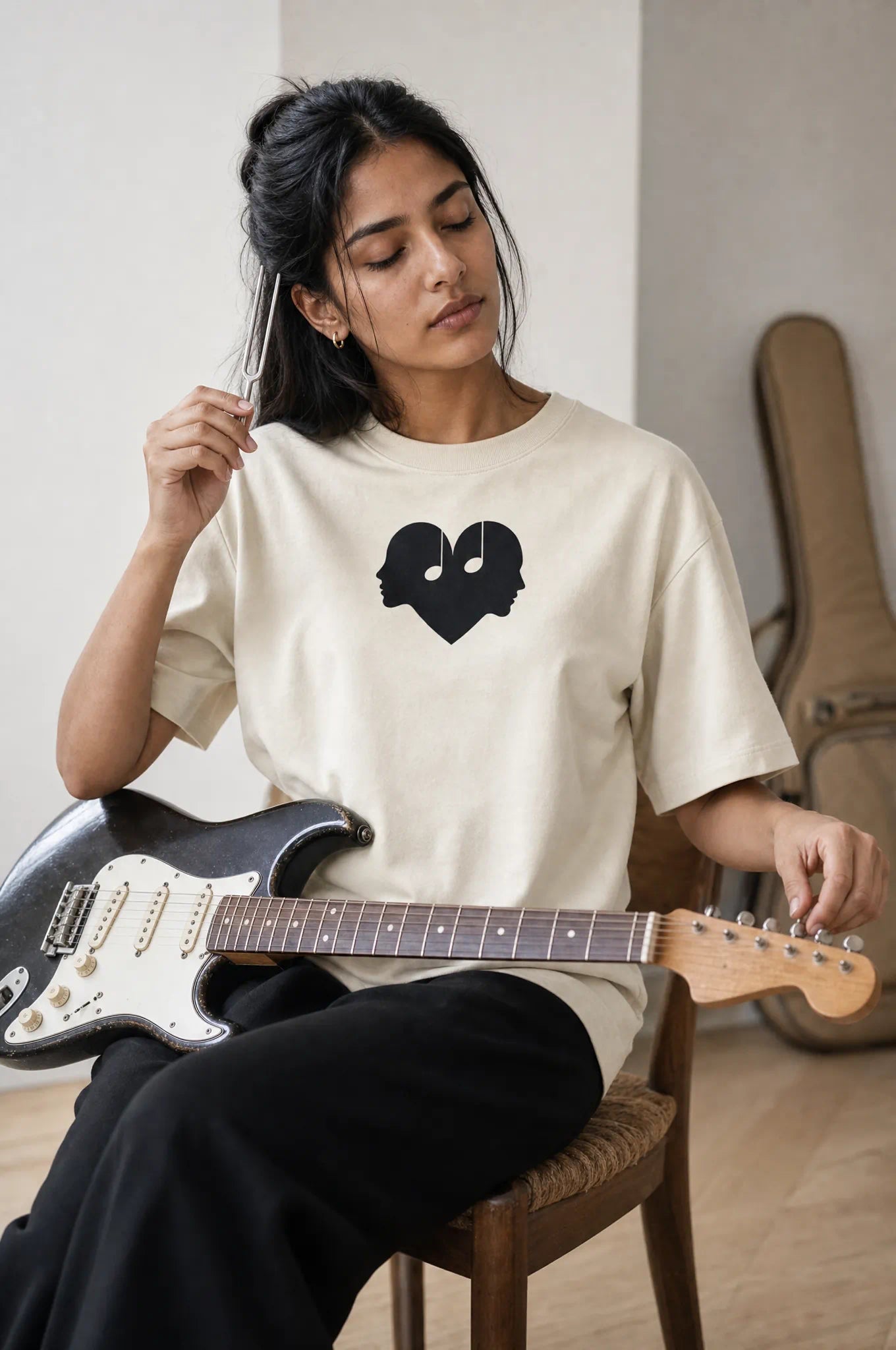 Woman tuning a guitar in the Alabaster Overture Oversized Tee
