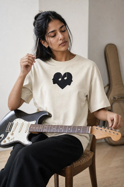 Woman tuning a guitar in the Alabaster Overture Oversized Tee