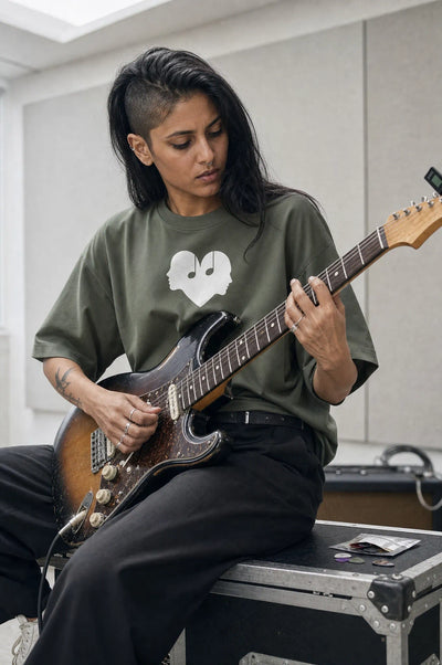 Woman playing an electric guitar in the Juniper green Overture Oversized Tee