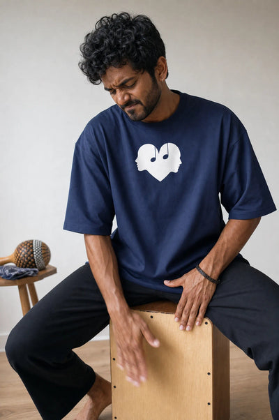 Man playing a cajon drum in the Midnight blue Overture Oversized Tee