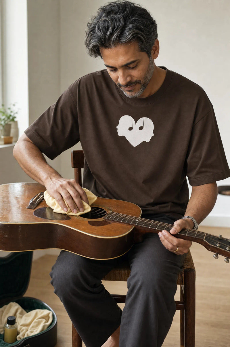 Man cleaning a guitar in the Mocha Overture Oversized Tee